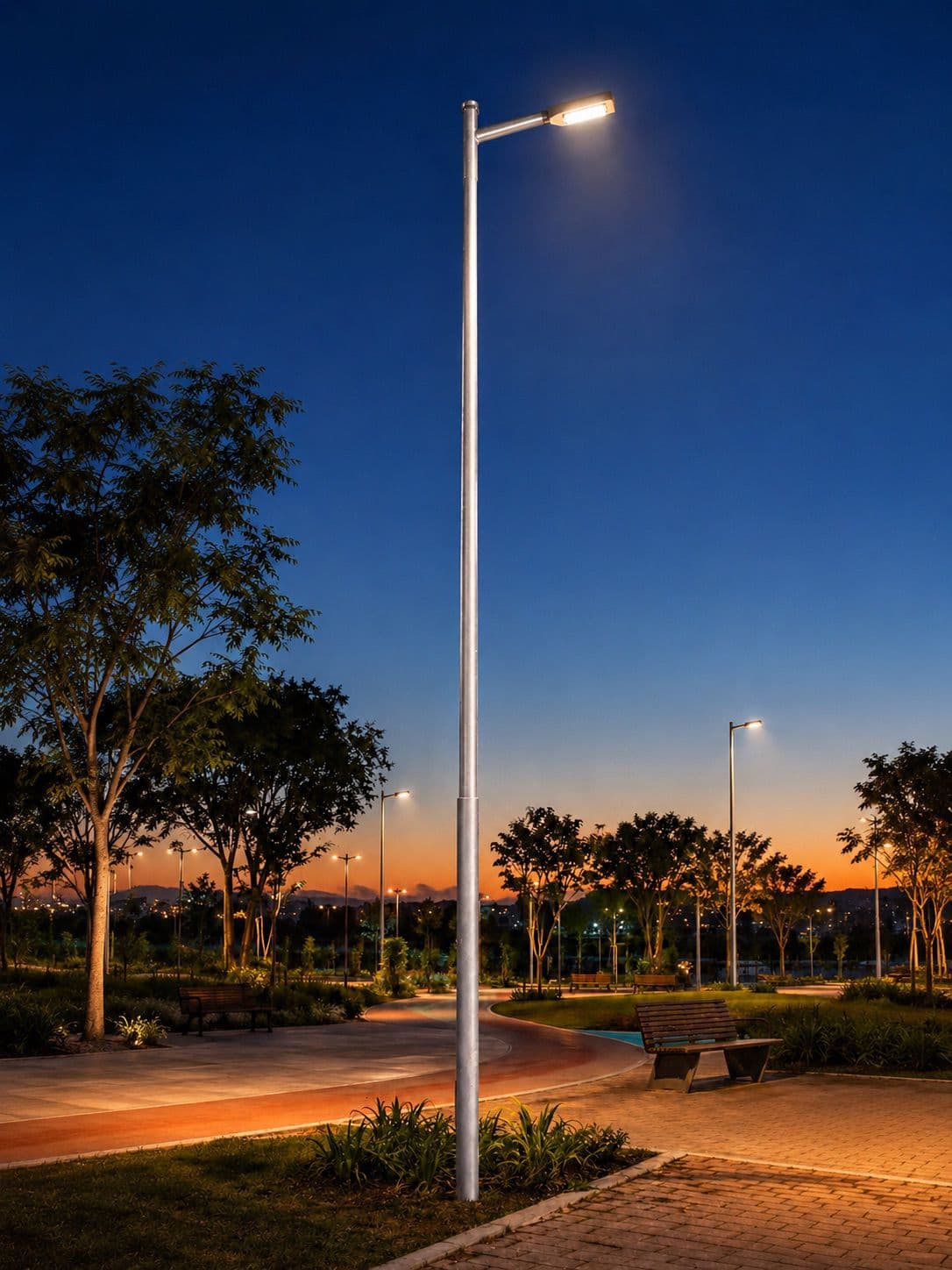 Poste com luminária instalado em área de convivência, fotografado ao entardecer